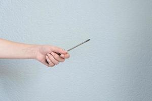 woman holding a screwdriver in her hand on gray background. photo