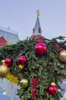 Christmas tree branches decorated with balls and garlands on red square background in Moscow photo