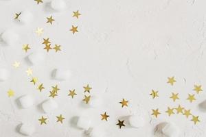 Festive white background with mini marshmallows and golden confetti stars. Greeting card with copy space photo