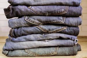 Stack of blue jeans on wooden shelf. Beauty and fashion clothing concept, toned photo
