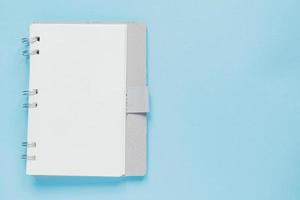 Clean spiral note book for notes and messages on blue background. Minimal business flat lay photo