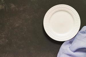 Top view of empty served plate, gray textile napkin on black concrete background. Copy space. photo