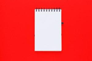 libreta de espiral limpia para notas y mensajes sobre fondo rojo. plano de negocios mínimo foto
