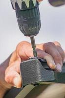 electric screwdriver in males hand. Worker with a hand tool assembling metal construction photo