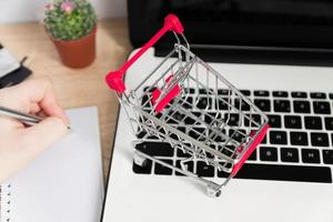 Small red shopping cart or trolley on laptop keyboard, Technology business online shopping concept photo