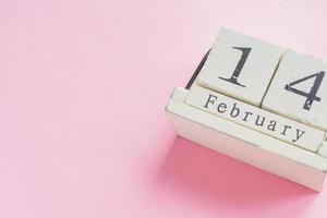 valentines day and holidays concept - close up of wooden calendar with 14th february date on pink background photo