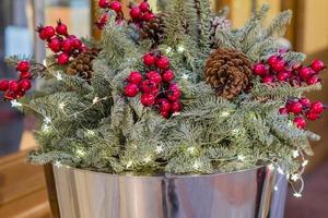 composición de ramo de navidad con ramas de árboles, cono de pino y bayas rojas en canasta de metal foto