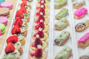 Pastry shop display window with variety of eclairs, macarons, tarts, selective focus photo