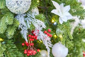 close up of christmas tree decorated with silver sparkling balls and garland with lights on. Festive background with copy space for your projects photo