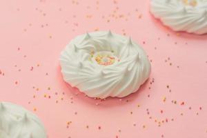 merengues caseros de aire blanco y decoraciones de confitería sobre fondo rosa foto