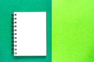 Clean spiral note book for notes on green background. Minimal business flat lay mock up photo