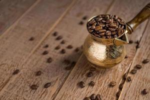 Close up of fresh roasted coffe beans in  cezve traditional turkish coffee pot on wooden table. photo