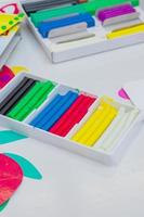 Set of colorful modeling clay in white paper box on a table photo