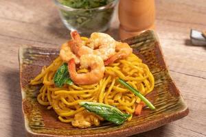 Fried noodles with shrimp in a plate on the table photo