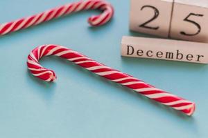 Wooden block calendar showing 25th of December. Christmas holiday. Greeting card with candy canes on blue backgeound. photo