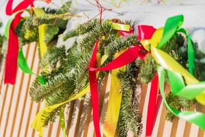 close up of a wooden fence decorated with colorful red, yellow and green ribbons covered with snow. photo