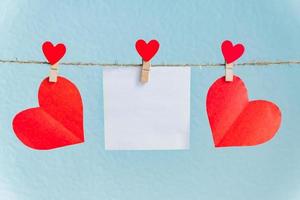 tarjetas en blanco en alfileres con corazones rojos. maqueta para texto y fondo azul para saludos del día de san valentín foto