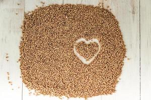 buckwheat background with drawn heart. Gluten free and healthy diet. Shallow depth of field. photo