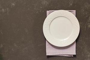 Top view of empty served plate, gray textile napkin on black concrete background. Copy space. photo