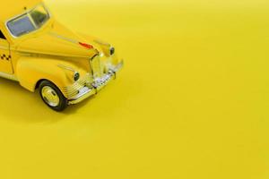 viejo taxi de coche de juguete amarillo retro sobre fondo amarillo con espacio de copia. enfoque selectivo, concepto de viaje foto