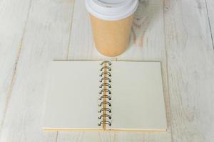 craft paper coffee cup and open notebook diary with copy space on wooden table photo