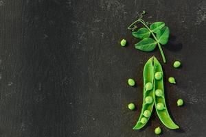 telón de fondo vegetal con espacio de copia para sus proyectos. Cerca de guisantes verdes maduros frescos sobre fondo negro foto