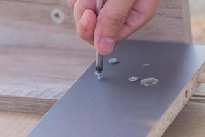 furniture assembling - Carpentry screws for a knock down wooden table. photo