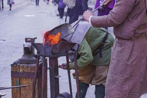 taller de herrería en la calle. gente en ropas tradicionales forja metal foto