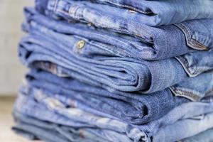 Stack of blue jeans on wooden shelf with copy space. Beauty and fashion clothing concept, selective focus photo