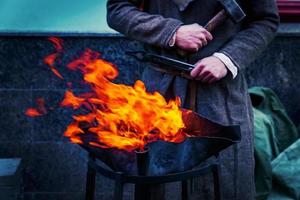 Blacksmith workshop on the street. People in traditional clothses forge metal photo