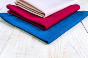 close up of cloth napkins of beige, blue and burgundy colors on rustic white wooden table. Shallow depth of field. photo