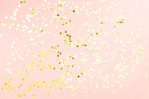 Holographic stars and gold sparkles on pastel pink background. Festive backdrop for your projects photo