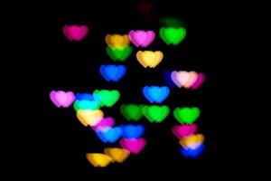 Multicolored hearts bokeh of blue and orange colores on black background. Texture for holidays photo