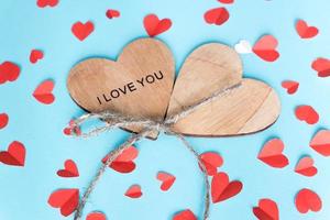 valentines day and holidays concept - two wooden hearts,  cut out paper small hearts on blue backround. Handmade decoration. photo