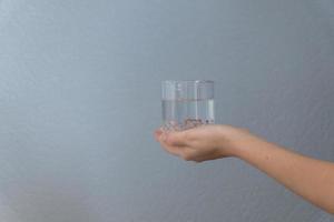 woman holding a glass of water in her hand on gray background photo