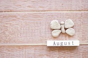 vista superior del calendario de madera con signo de agosto, mariposa de arcilla foto