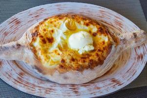 Traditional Georgian cuisine. Ajarian khachapuri on a plate. top view. Open pie with cheeze and egg photo