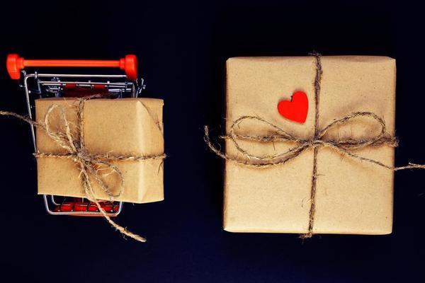 Female hand hold a box wrapped in red paper and tied with a red