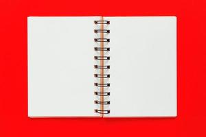 Clean spiral note book for notes and messages on red background. Minimal business flat lay photo