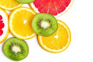 Top view of citrus slices - kiwi, oranges and grapefruits isolated on white background with copy space. Fruits backdrop photo