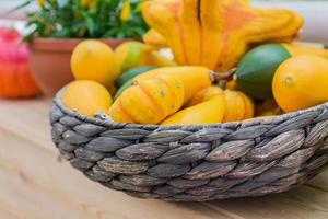 An assortment of small decorative pumpkins in a basket. Autumn interior composition. photo