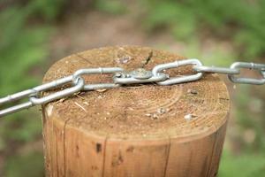 detail of fence. Meta chain on wooden stump for protection photo