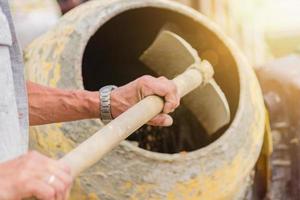 construction worker shovels the sand into the concrete mixer. process of creating cement on the construction site photo