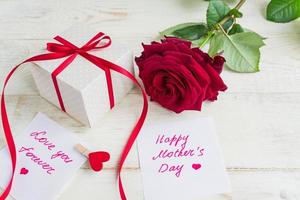 Beige polka dot gift box with red ribbon bow and bautiful red roses on wooden background. Greeting card for Mother's day photo