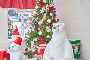 oso polar con árbol de navidad decorado con bolas y lazos y regalos. interior de la sala de navidad. foto