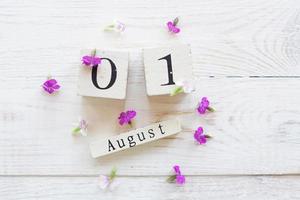 1 August, colorful background with cube wooden calendar and pink flowers photo