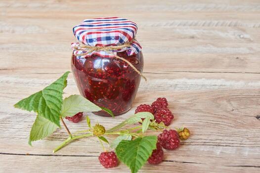 Raspberry jam and fresh raspberry branch on a rustic wooden table photo
