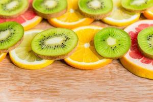frame with slice of oranges, lemons, kiwi, grapefruit on wppden background photo