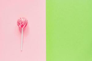 Sweet tasty pink lollipop on green and pink background. Minimal flat lay with copy space photo