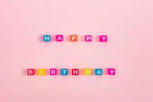 Happy birthday mom inscription made of colorful cube beads with letters. Festive pink background concept with copy space photo